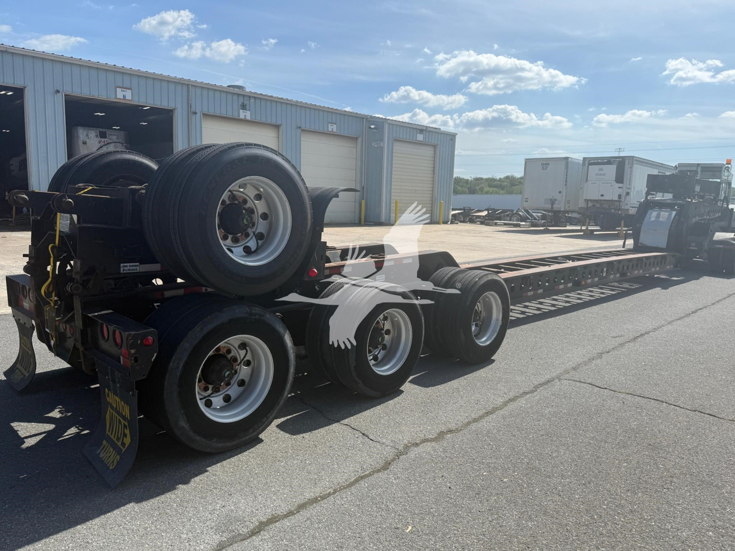 Etnyre beam trailer in an open lot with spare wheels mounted on rear and long trailer deck.