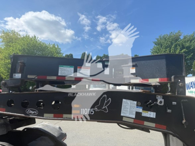 Trailer hitch showing BlackHawk 110105 beam with warning labels and stickers on a lowboy trailer frame.