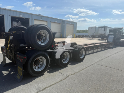Etnyre beam trailer in an open lot with spare wheels mounted on rear and long trailer deck.