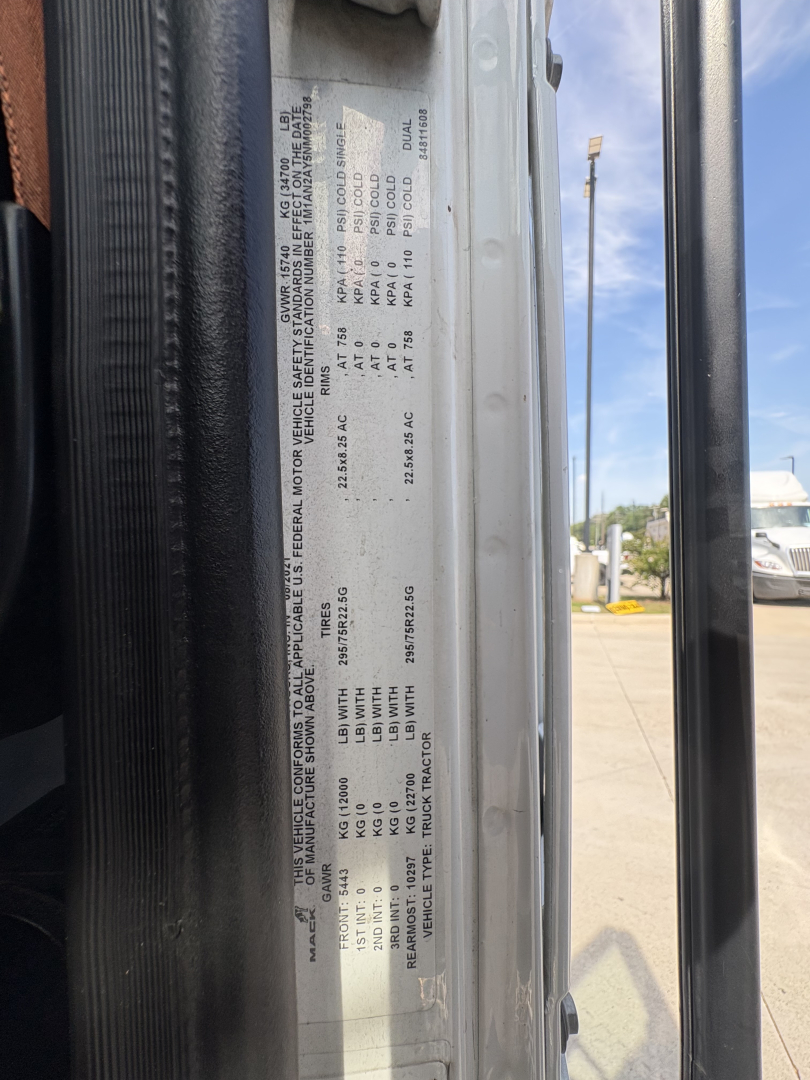 Truck cab door sticker with vehicle specifications and weights; text includes VIN, axle ratings, and model details. Side view of door jamb with labels and numbers visible.