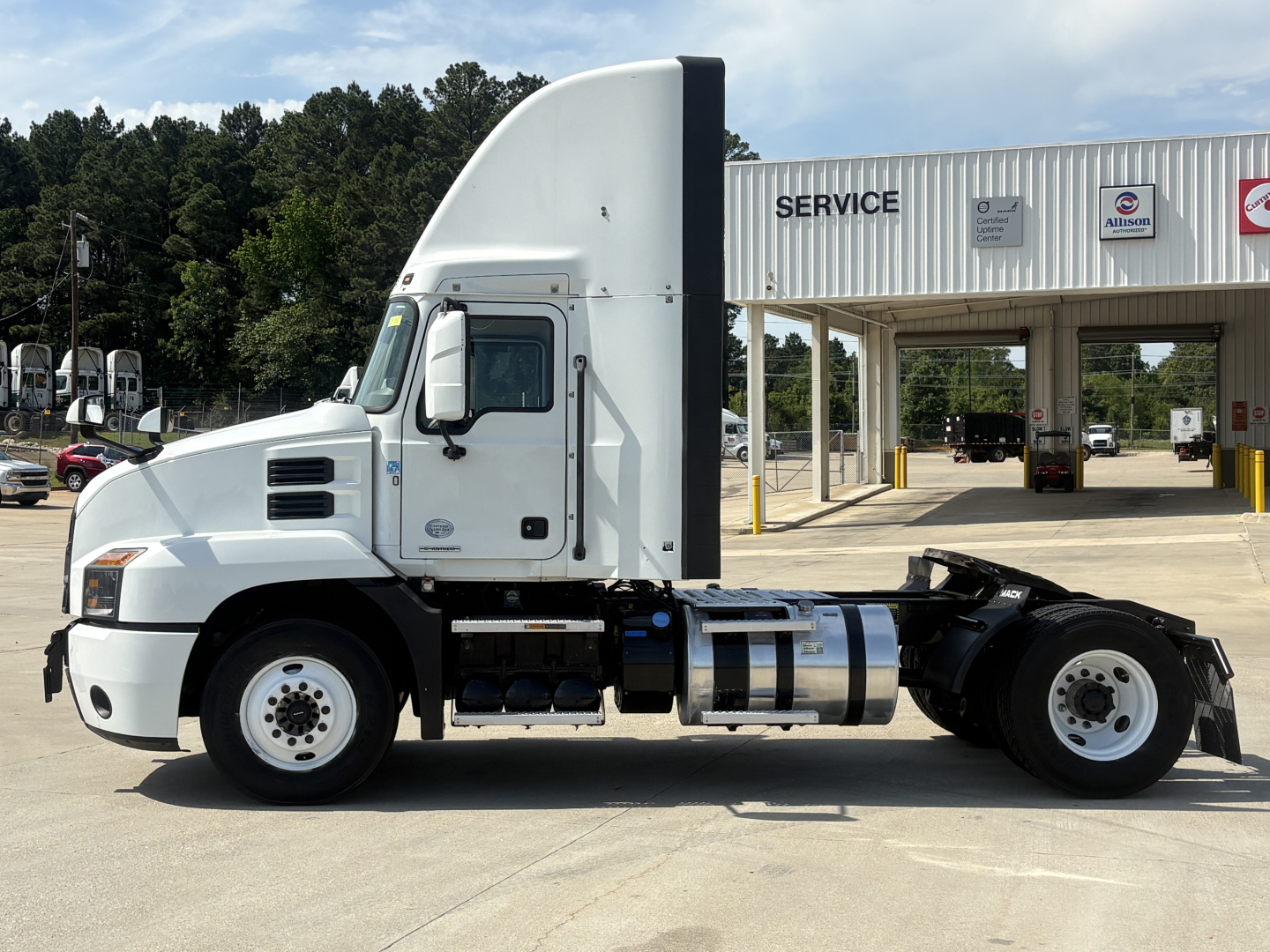 Side view of a 2022 Mack AN42T conventional daycab truck in a dealership lot showing cab, fuel tanks, and chassis.