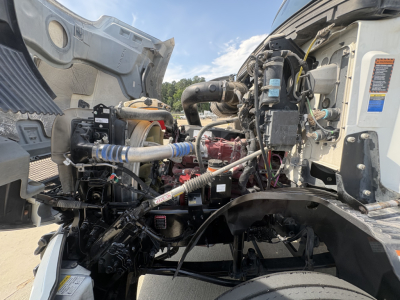 Engine bay with hoses and components of a Mack AN42T daycab truck showing engine block, hoses, and various labels.