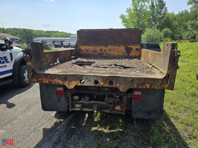 Rear view of a rusty dump truck bed on a 1990 Chevrolet C/K 3500 Series dump truck showing tail lights and hitch area.