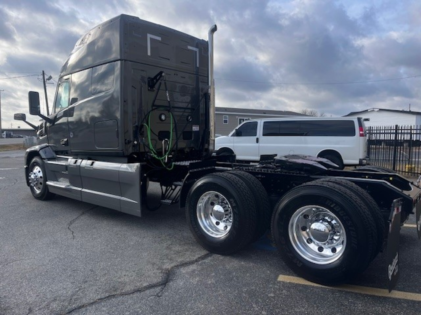Mack PR64T76M sleeper cab tractor with dual rear axles and chrome wheels, front cab side view showing green air lines and fifth wheel area.