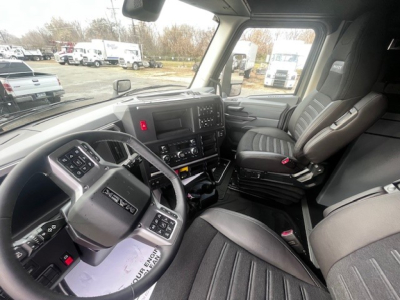 Truck cab interior of a 2026 Mack PR64T76M showing steering wheel, dashboard, and driver seat with controls and displays visible.