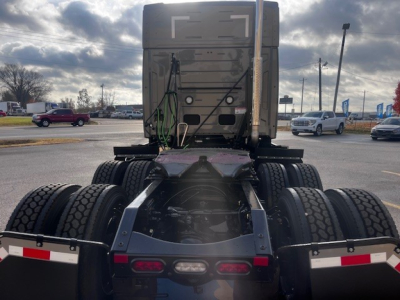 Truck chassis and rear view showing fifth wheel and multiple rear axles on a new Mack PR64T76M tractor, with tires and undercarriage visible.
