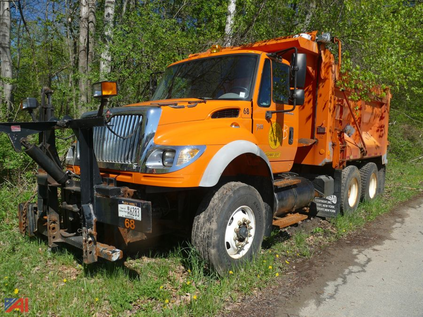 Orange International dump truck showing front and driver side with plow/bumper attachment and dump bed, VIN 1HTWYAHT97J424162 visible on listing.