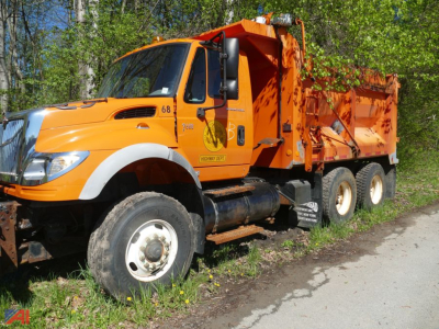 Orange International dump truck in-service showing front radiator area and dump bed with black tires and white rims.