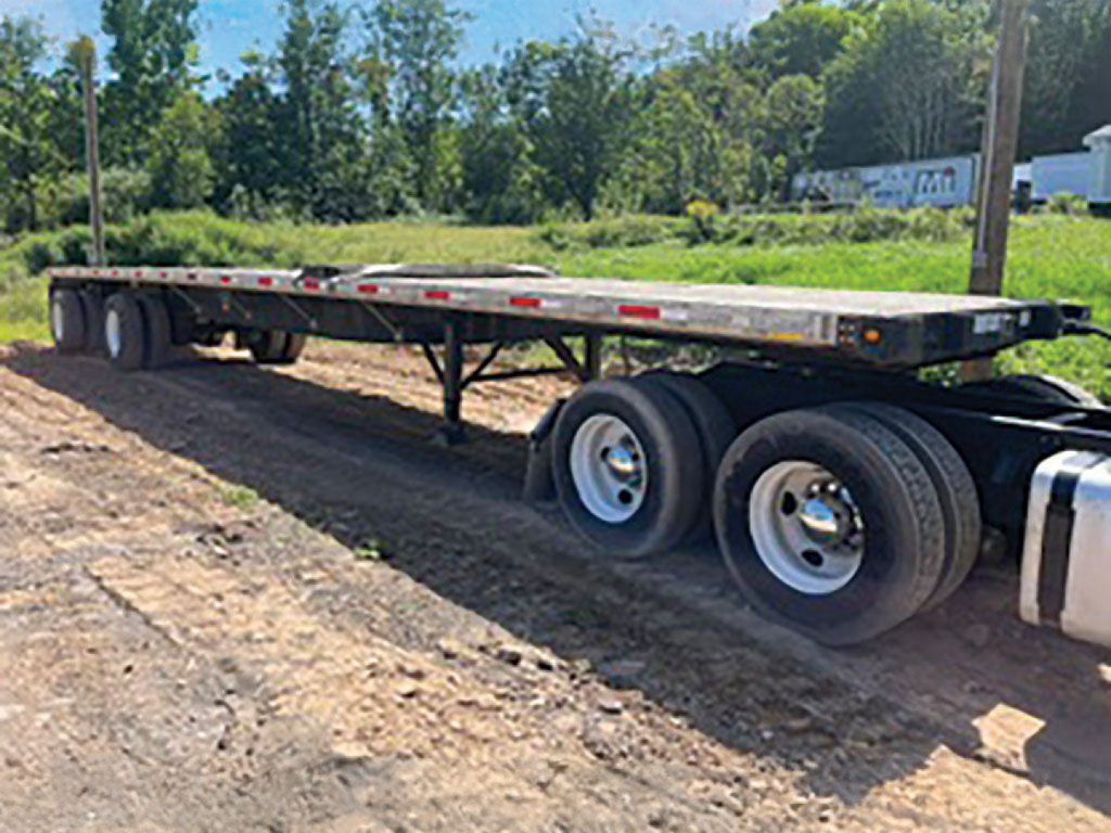 Great Dane flatbed trailer with aluminum and steel composite deck showing tandem axle wheels and side rails.
