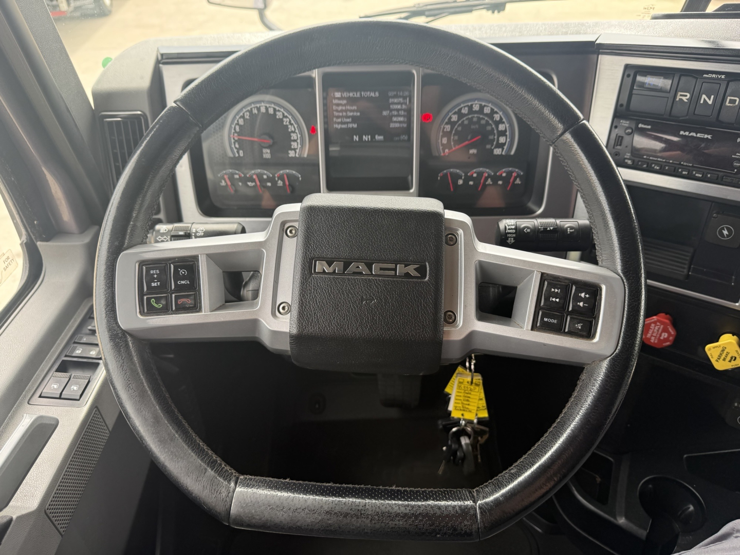 Mack AN64T70 truck interior steering wheel and dashboard view showing Mack logo on steering wheel and instrument cluster.