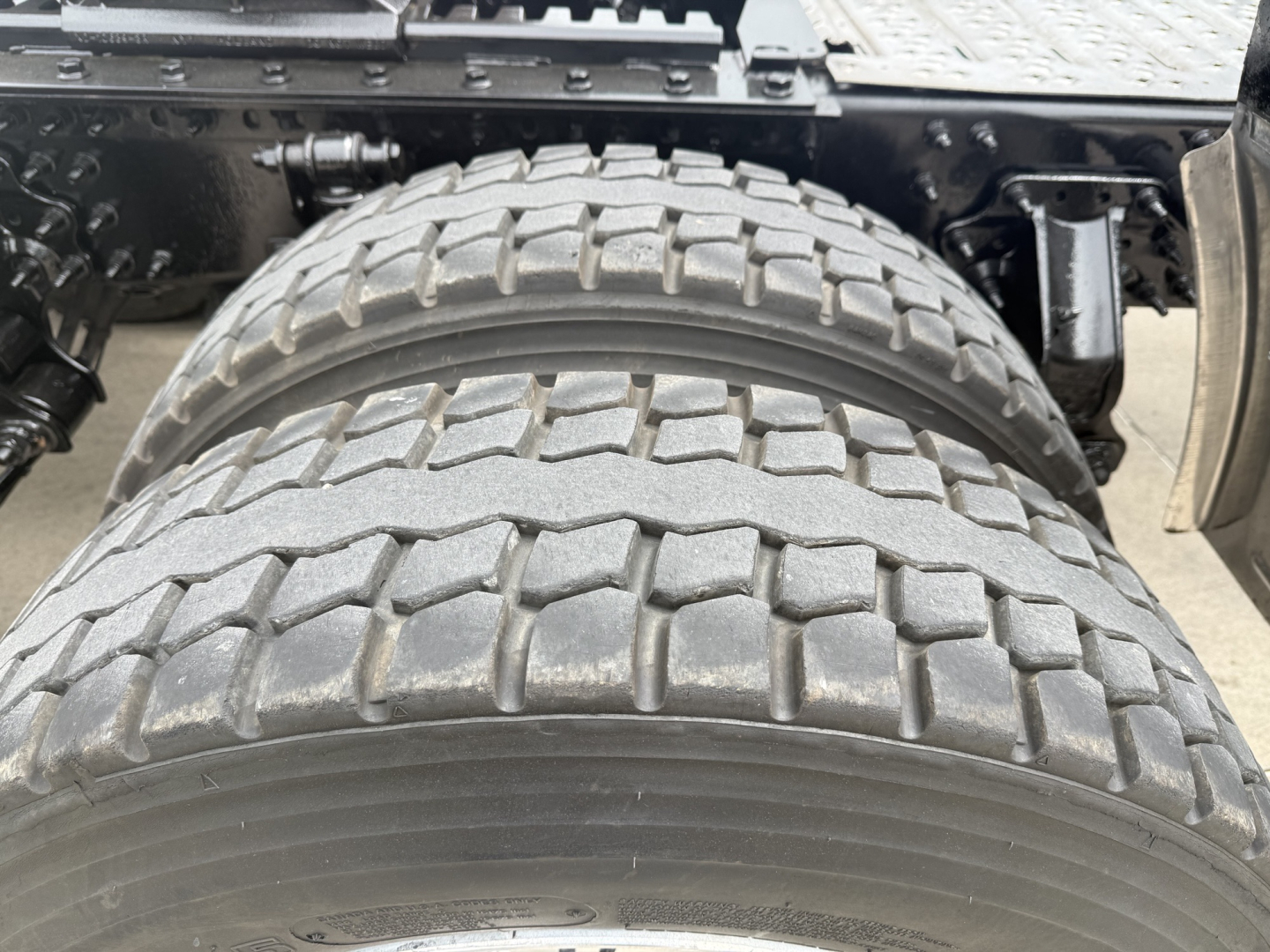 Rear dual rear tires on a 2023 Mack AN64T70 sleeper tractor showing tread pattern and mounting over/under the frame