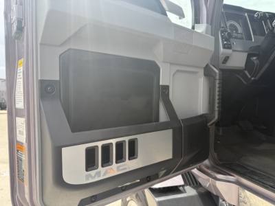 Truck door panel with Mack logo and control area; interior cabin dash visible in background.