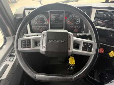 Mack AN64T70 truck interior steering wheel and dashboard view showing Mack logo on steering wheel and instrument cluster.