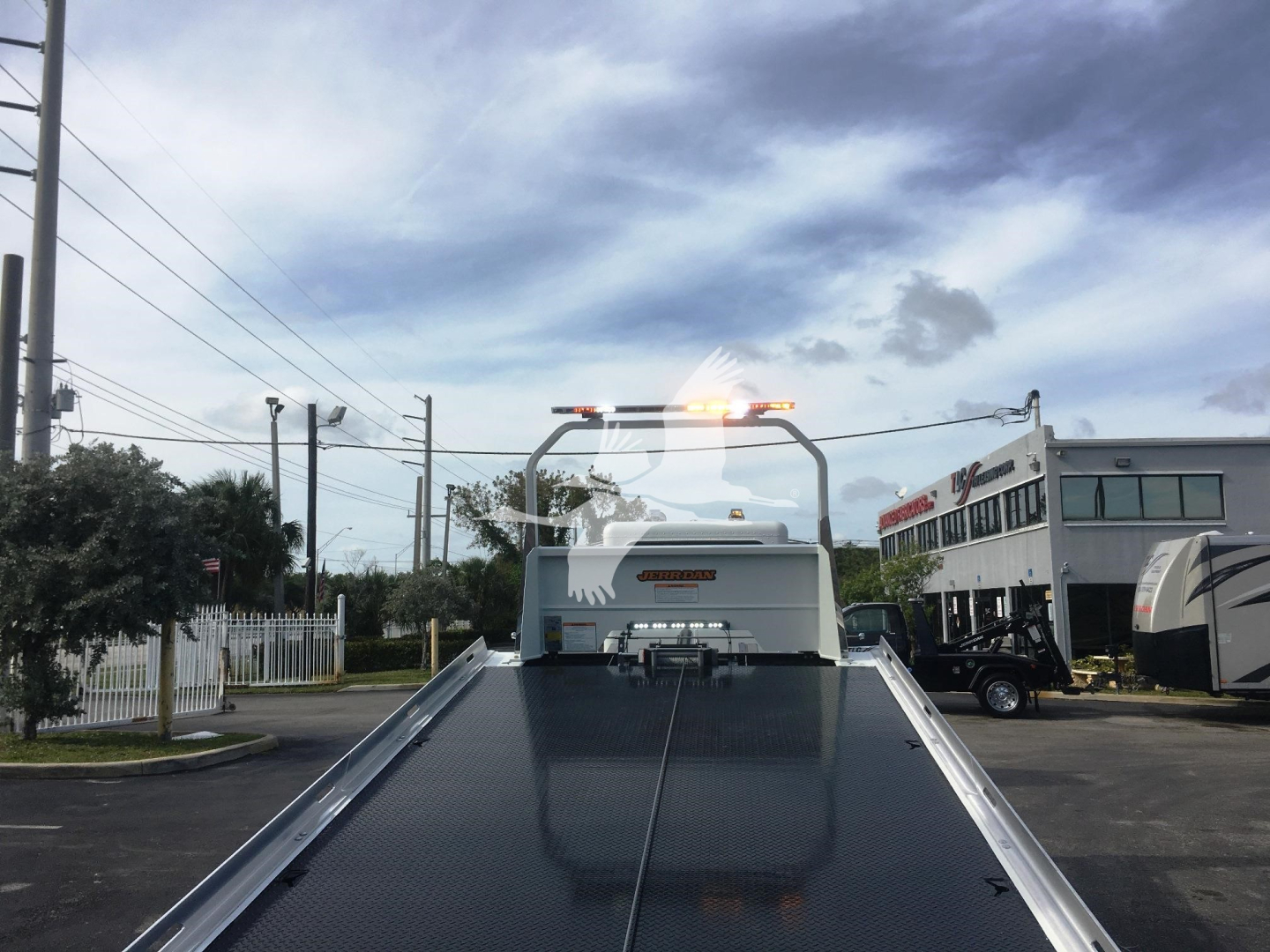 Peterbilt 337 rollback truck bed with hydraulic winch and rear cab, empty bed surface, dealership lot in background