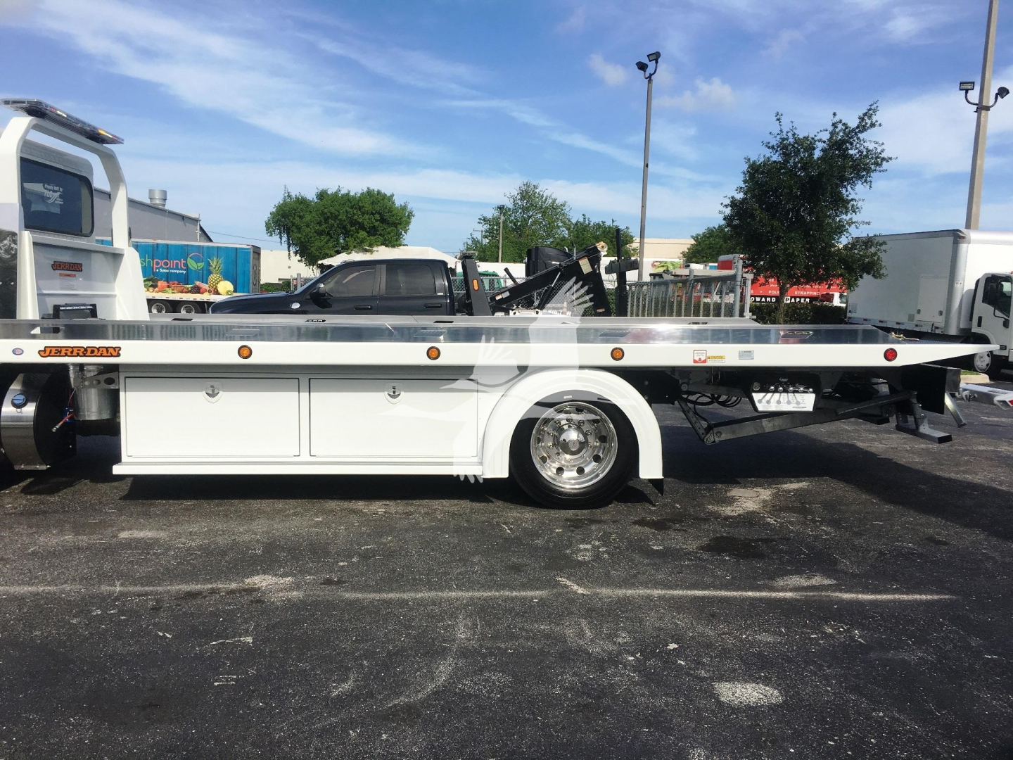 Peterbilt 337 rollback truck side view showing long flatbed, white fuel/tool compartments, chrome wheel, and side decals. Visible text includes Peterbilt branding on cab and stock/lot details not in the image.