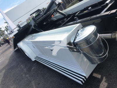 Truck body side panel with metallic silver storage box and cylindrical fuel tank mounted on a Peterbilt 337 rollback vehicle.