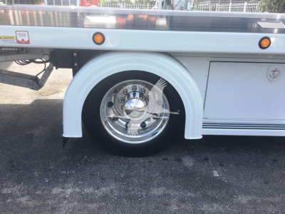 Peterbilt 337 rollback truck wheel and rear fender view showing white wheel arch, chrome wheel, and side panel. No text clearly legible other than small stickers.