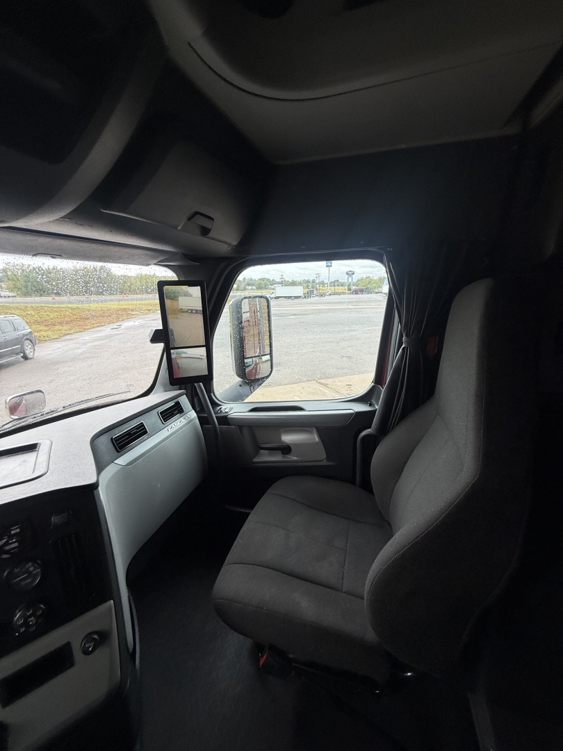 Freightliner Cascadia126 truck cabin view showing driver seat and dashboard with side mirror