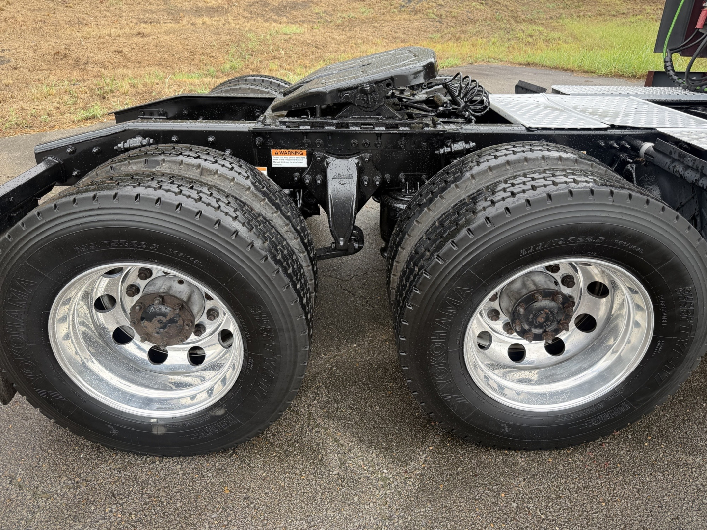 Truck chassis showing dual rear wheels and suspension components of a Freightliner Cascadia126 in-service, with chrome rims and tires visible.