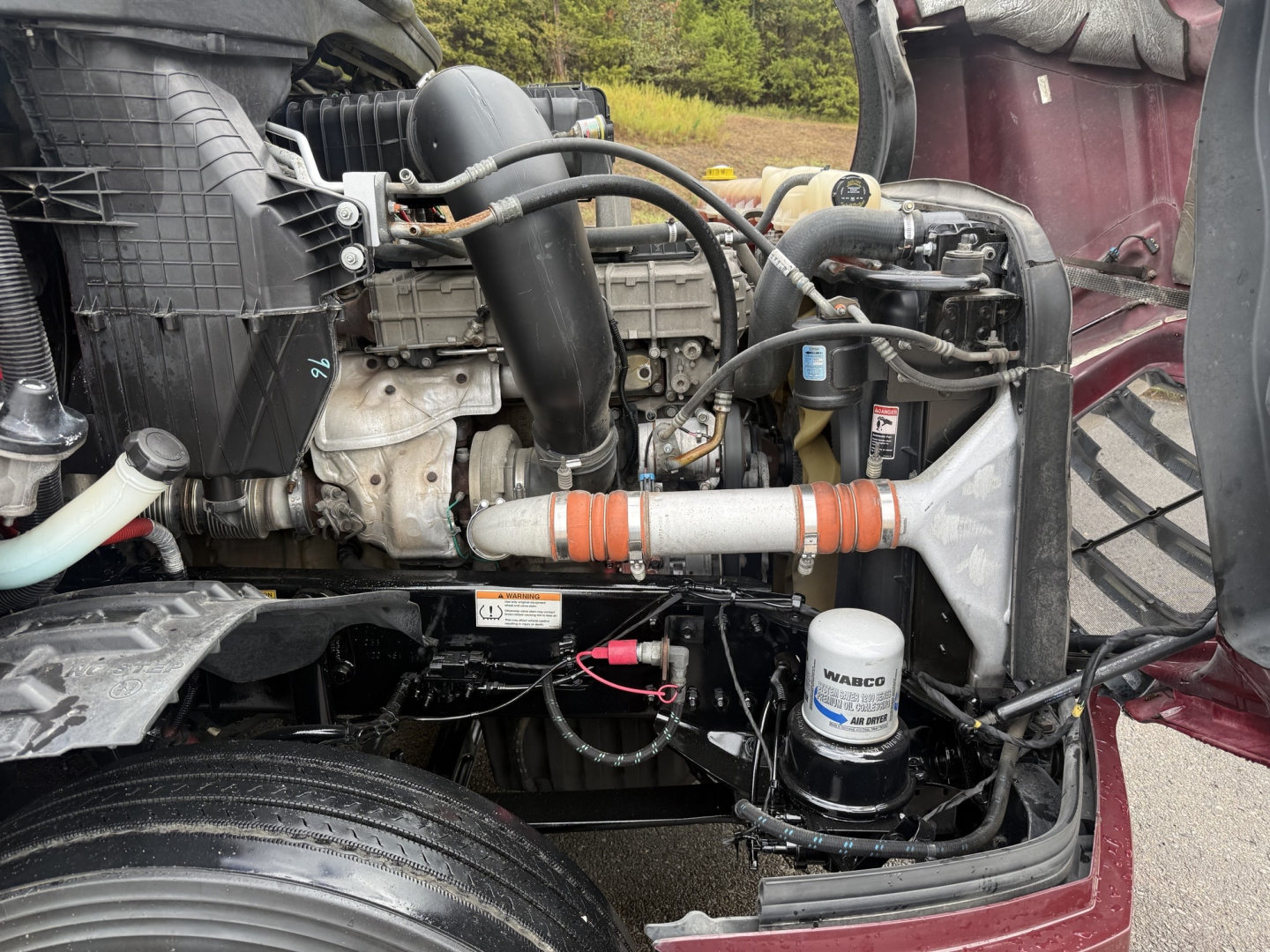 Freightliner Cascadia126 engine bay showing air intake, coolant hoses, oil filter, and auxiliary components.