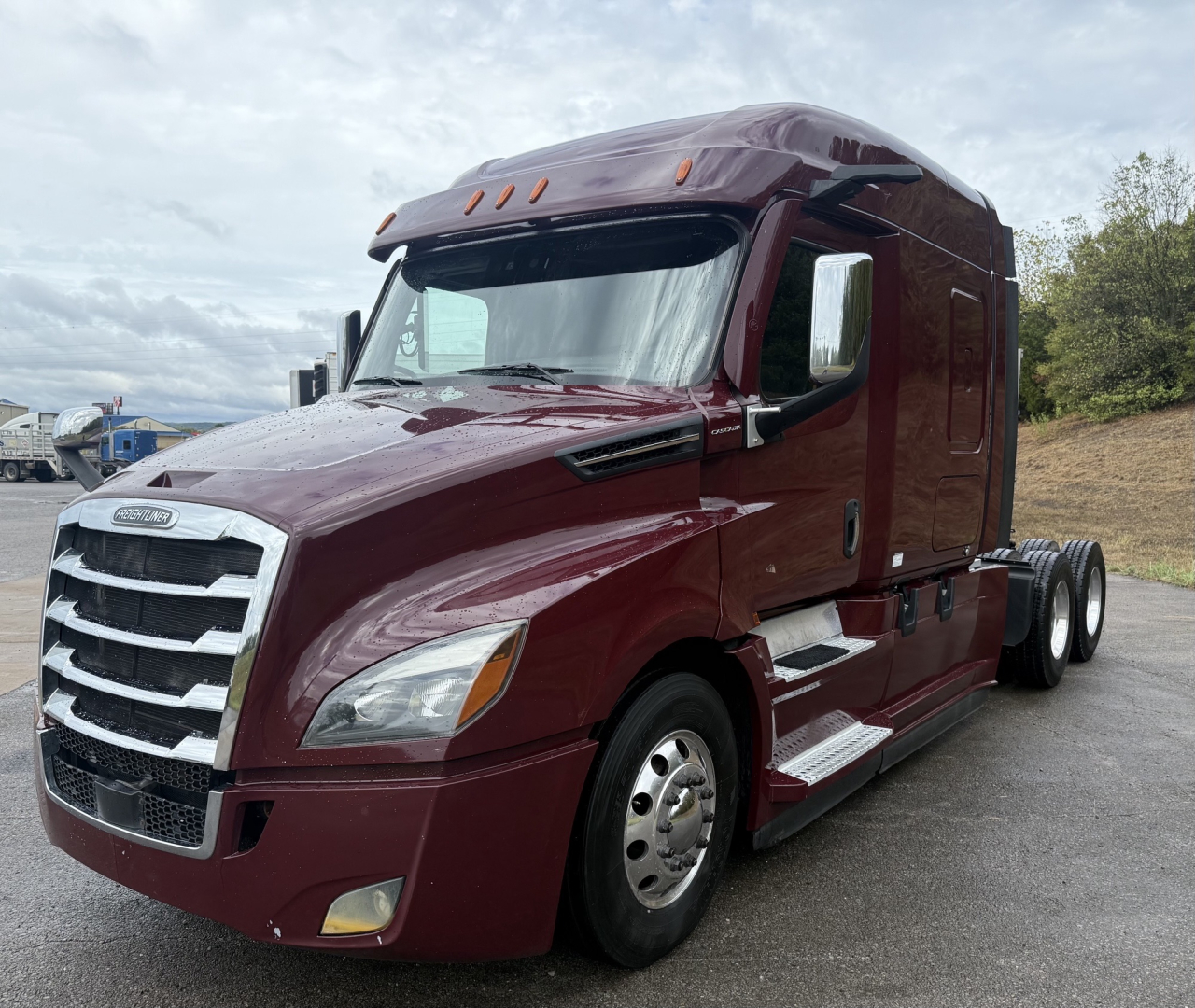 Curtain-side Freightliner Cascadia 126 truck in maroon, front three-quarter view; visible text includes Freightliner emblem on grille, no other legible labels.