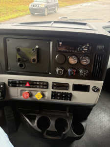Dashboard of a Freightliner Cascadia126 truck showing control dials, switches, and cup holders; no visible model labels or badge text identifiable.