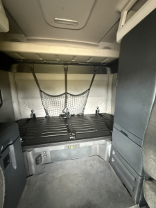 Freightliner Cascadia126 sleeper cab interior showing bunk area with storage net, side panels, and cargo space.