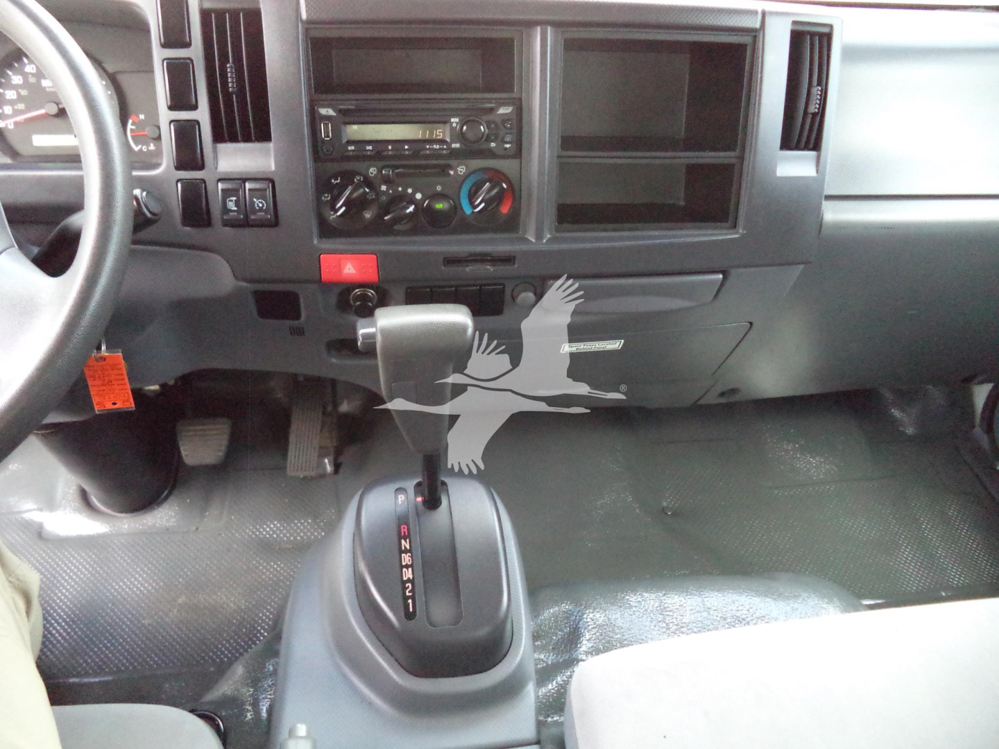 Vehicle interior showing dashboard with steering wheel, center console, gear shifter, and driver-side floor with pedals.