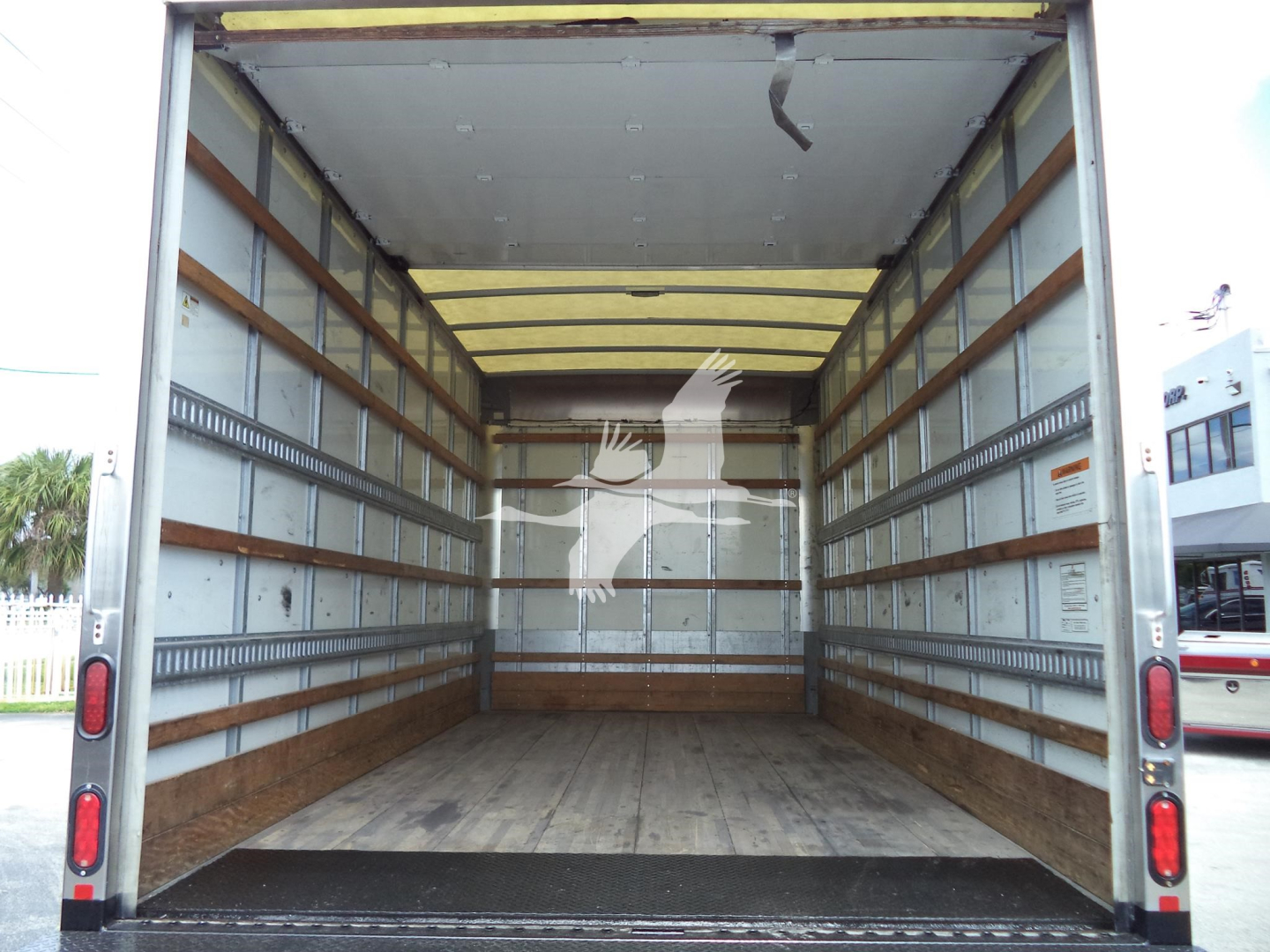 Isuzu NPR-HD box truck cargo area with empty wooden floor and metal side rails.