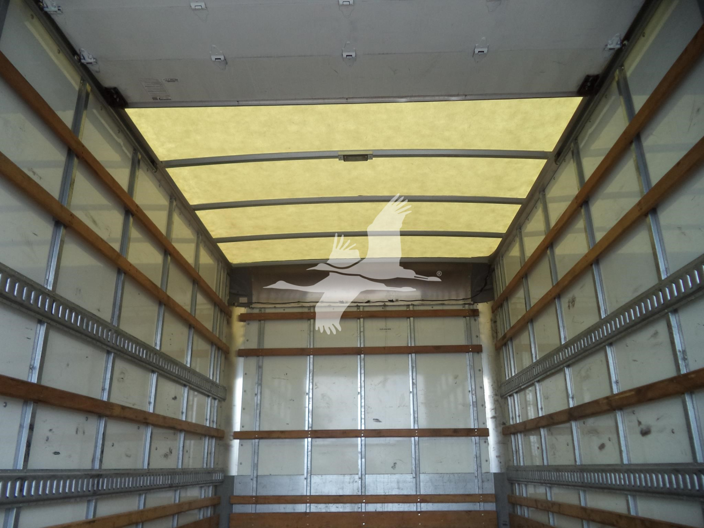 Isuzu NPR HD box truck cargo area interior showing metal walls and wooden support battens.