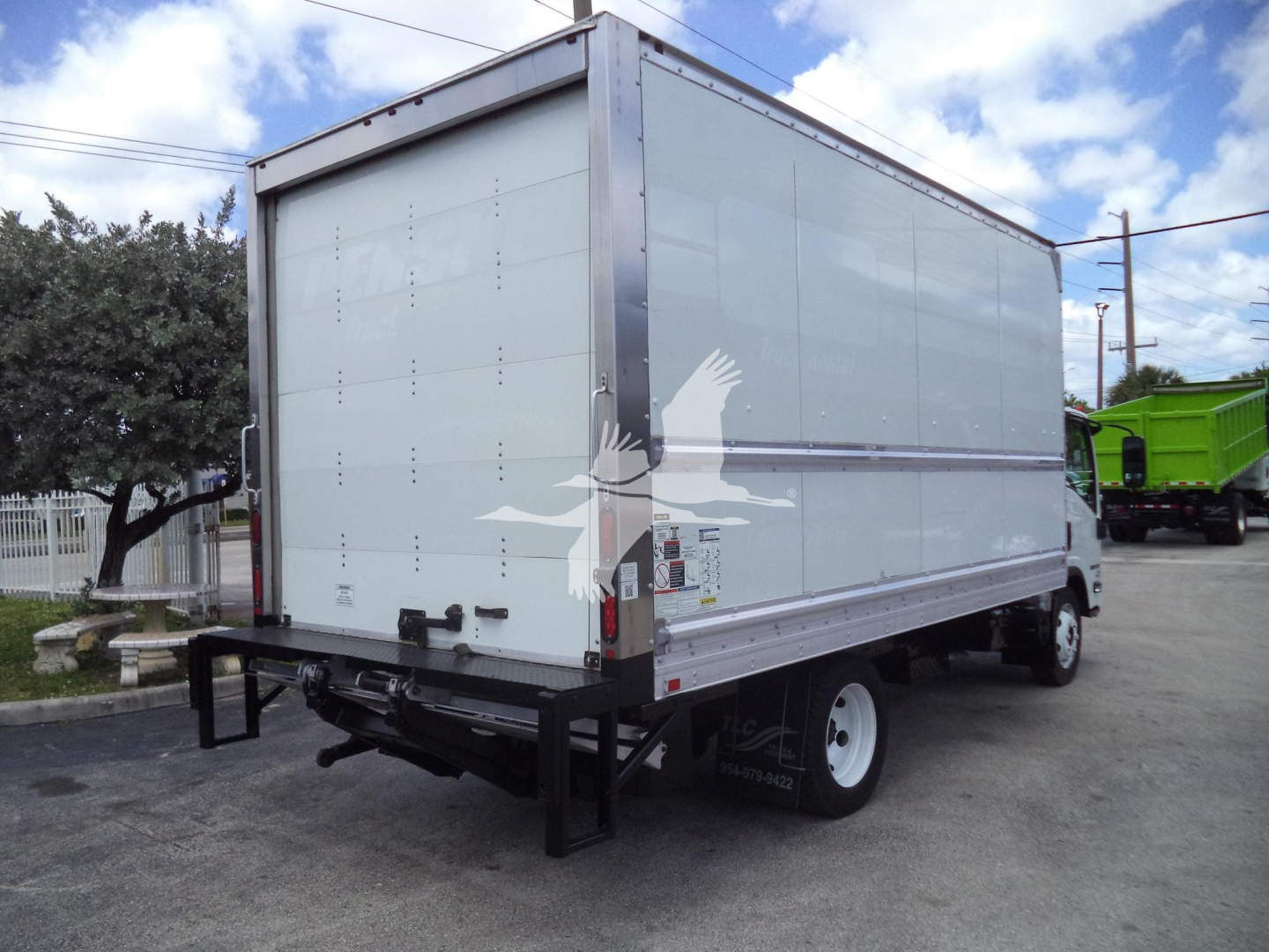 Isuzu NPR HD box truck rear and side view showing box cargo area with reflective trim and rear bumper.