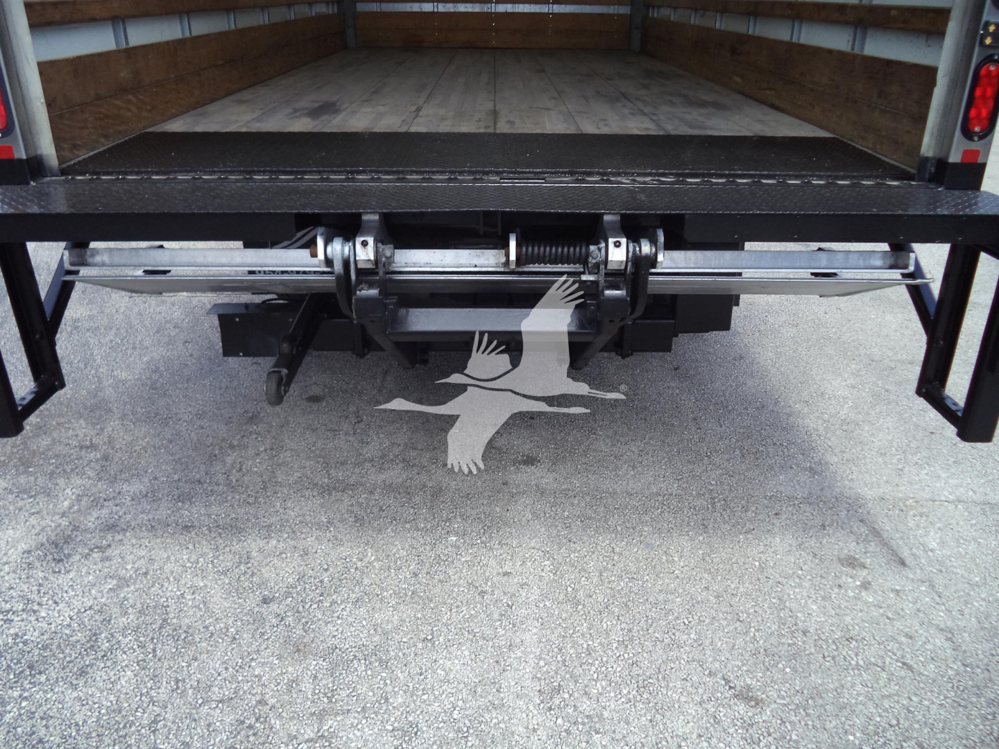 Isuzu NPR HD truck bed with rear undeck mechanism and hydraulic hitch components visible in the cargo area.