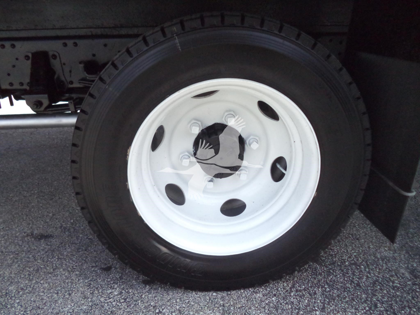 Isuzu NPR HD truck wheel and tire with white steel rim and black tire. Visible round hub with center cap and lug nuts.