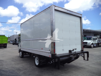 Isuzu NPR HD box truck rear view showing plain white cargo box with a large graphic of a bird on the side and bumper hitch, street and other trucks in background.