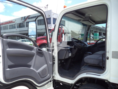 Isuzu NPR HD cab interior and open driver door showing steering wheel, dashboard, and gray seat in a used truck.