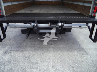 Isuzu NPR HD truck bed with rear undeck mechanism and hydraulic hitch components visible in the cargo area.