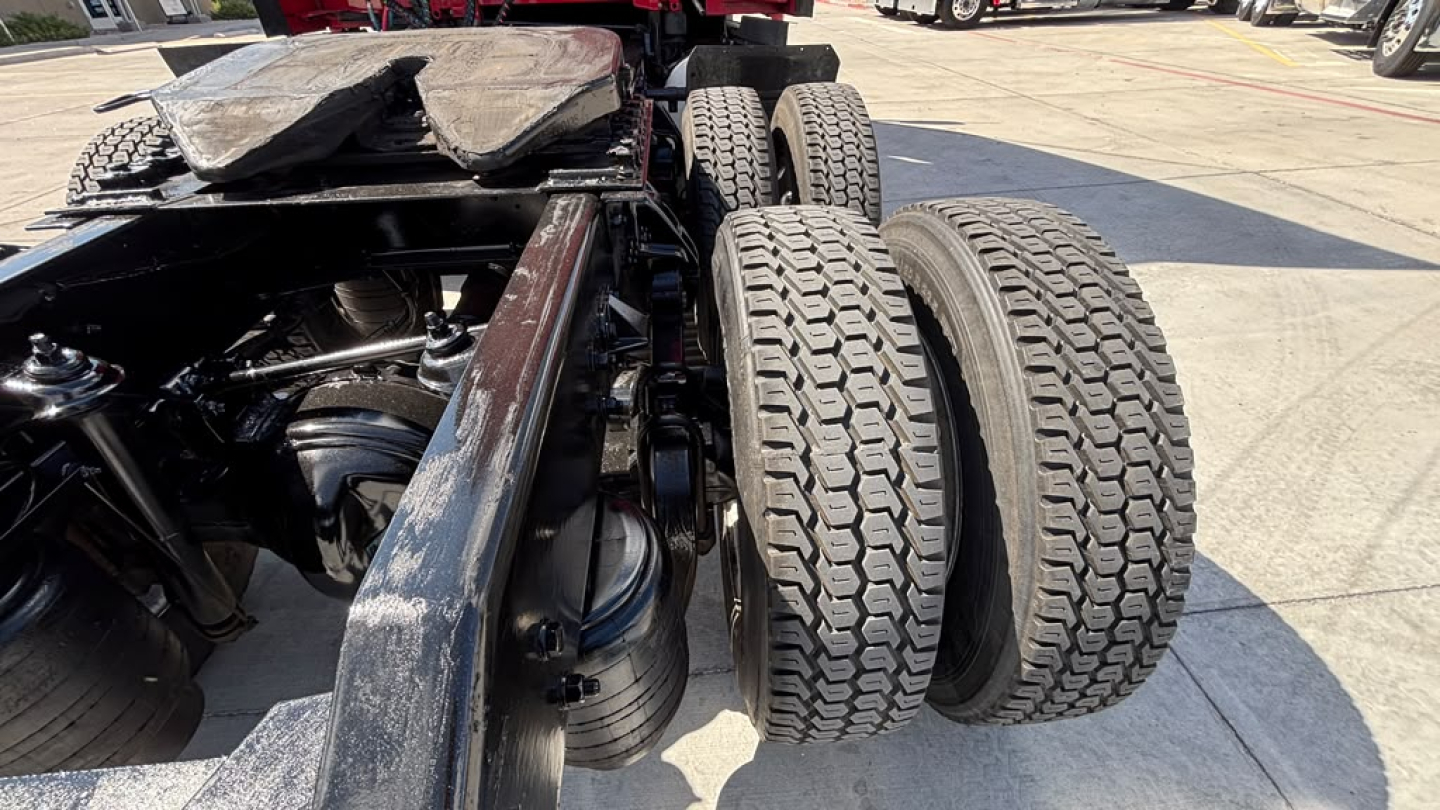 Kenworth T680 chassis with dual rear axles and exposed engine bay area; diesel tanks and tires visible; hardware and frame components in view.