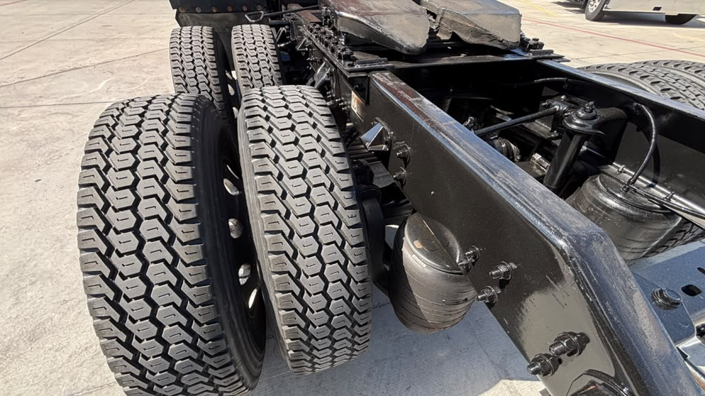 Wheel end view of a 2022 Kenworth T680 conventional sleeper truck showing dual rear axles and heavy-duty tires.