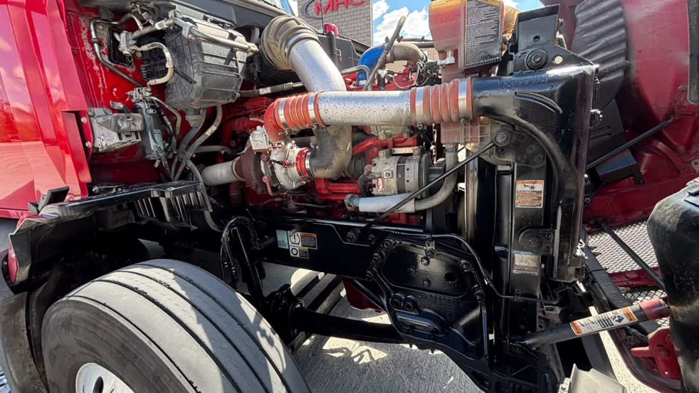 Kenworth T680 engine bay showing front suspension and diesel engine components with hoses and hoses clamps visible.