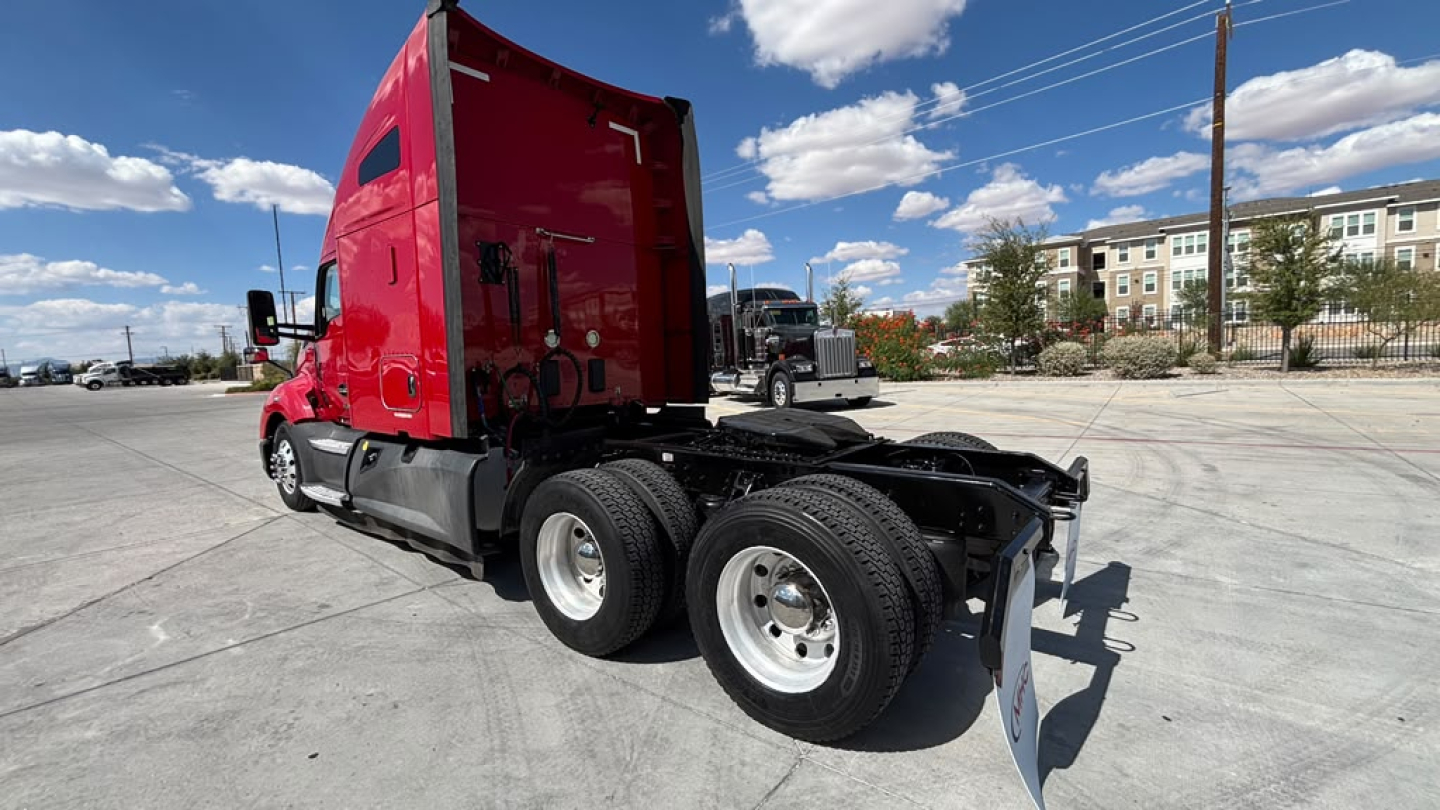 Kenworth T680 tractor with red sleeper cab, rear view shows dual rear axles and fifth wheel hitch, no trailer attached.