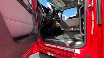 Kenworth T680 cab interior showing driver seat and dashboard from open door.