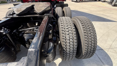 Kenworth T680 chassis with dual rear axles and exposed engine bay area; diesel tanks and tires visible; hardware and frame components in view.