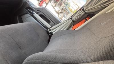 Cab interior of a 2022 Kenworth T680 with fabric seats and parked curtains in sleeper area; no clear engine or labels visible.