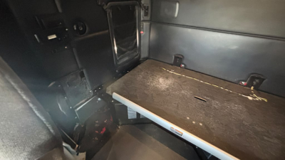 Kenworth T680 sleeper cab interior cargo area with black panels and a metal rail, showing a flat floor and a side wall storage area.