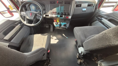 Kenworth T680 truck interior showing steering wheel, dashboard, center control cluster, driver and passenger seats, and floor pedals.