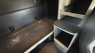 Kenworth T680 cargo area showing interior storage shelves and sleeper compartment with steps, cargo floor, and tie-down points.