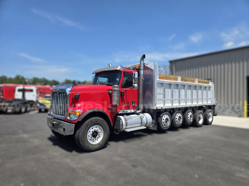 Dump truck in red cab with silver dump bed, side view showing multiple axles and heavy-duty tires.