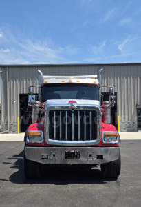 Front view of a red and white 2018 International HX dump truck showing bold chrome grille and bumper.