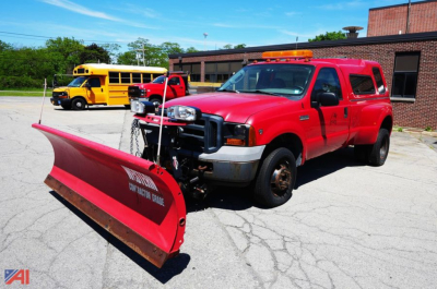 Ford F-350 XL SD dually pickup with a front-mounted plow and utility cap, red body, daytime scene.