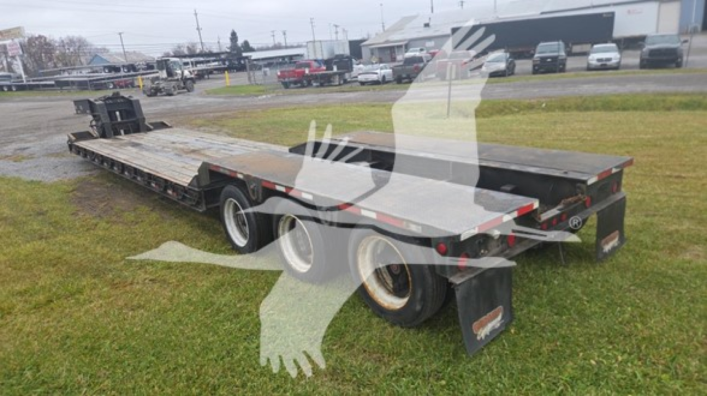 Rogers 50 Ton lowboy trailer in a yard, flatbed with wooden deck, dual rear axles, side rails, and rear ramps visible.